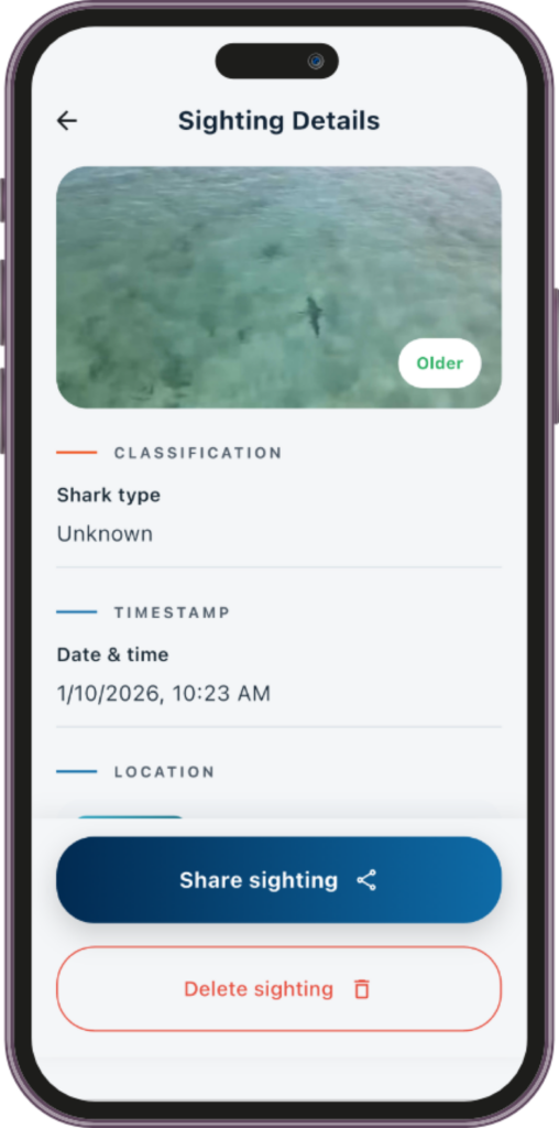 Mobile app sighting details screen showing an image of a shark, classification as unknown, timestamp, location, and options to share or delete the sighting.