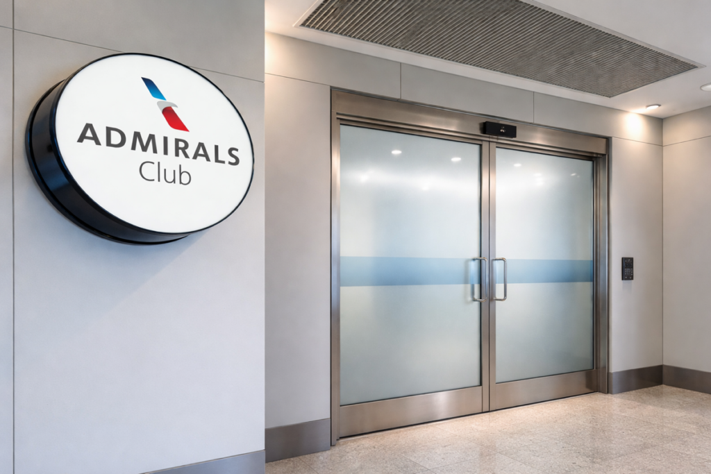 Entrance to an American Airlines Admirals Club featuring a round illuminated sign and closed frosted glass double doors in a modern airport concourse.